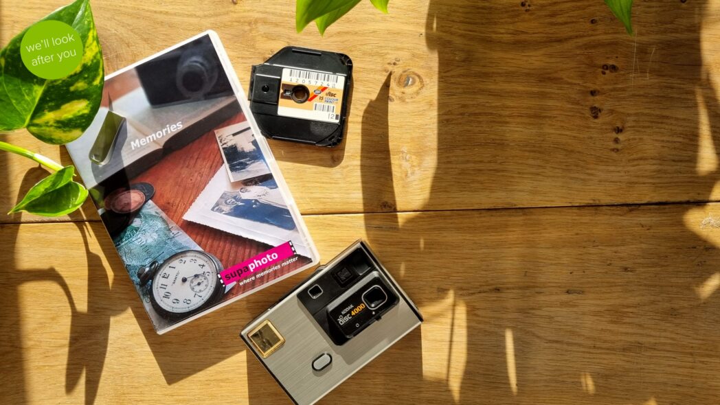 disc film, vintage camera and a dvd case which are displayed on a wooden table